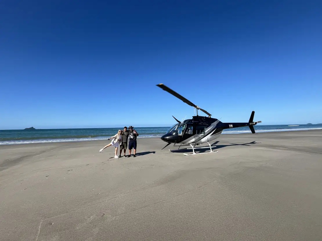 Helicopter landing on a remote beach during the Kaimai Classic Scenic Flight